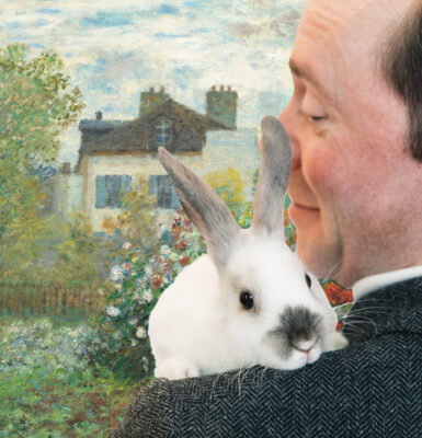 Actor Tom Keenan holds a white bunny on his shoulder and smiles at it.